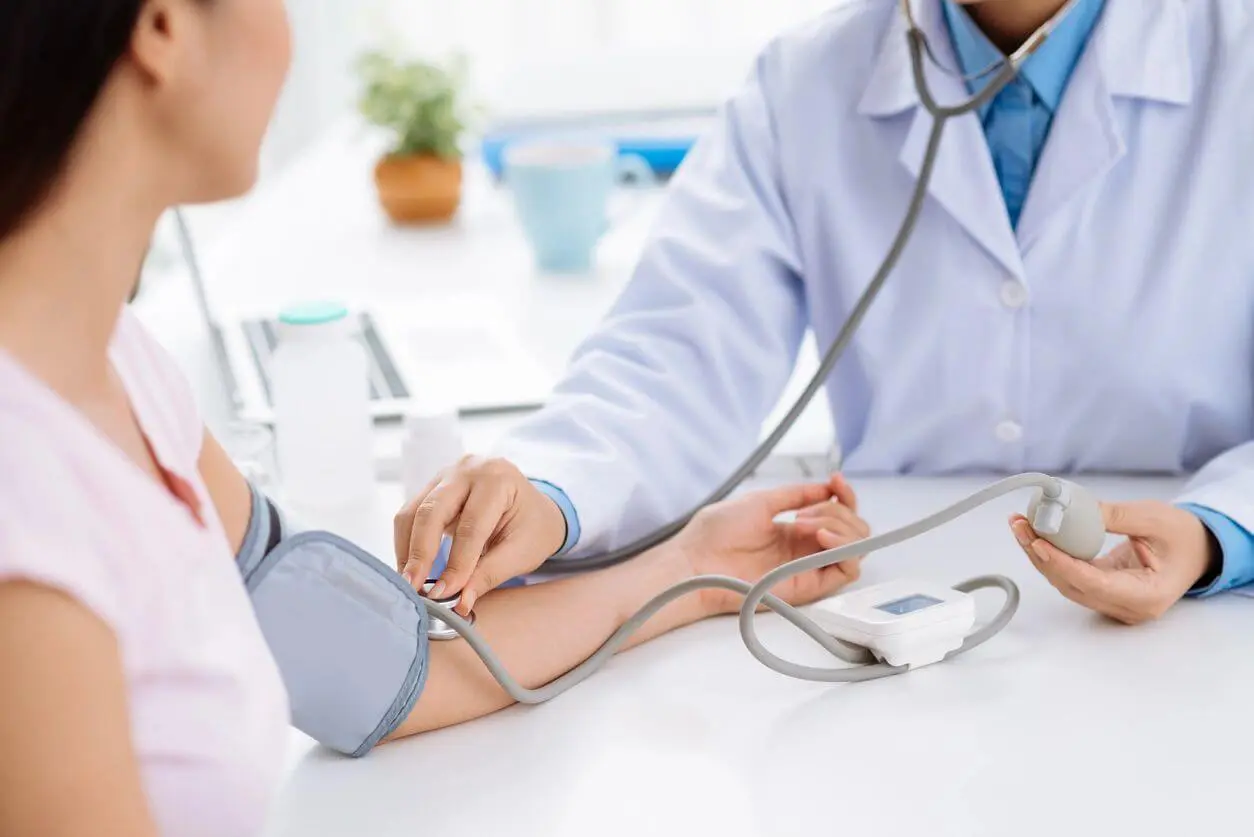 A doctor is taking blood pressure of someone else.