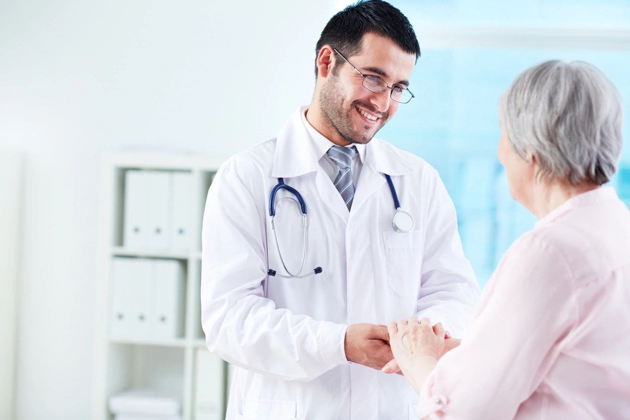 A doctor is shaking hands with an older woman.